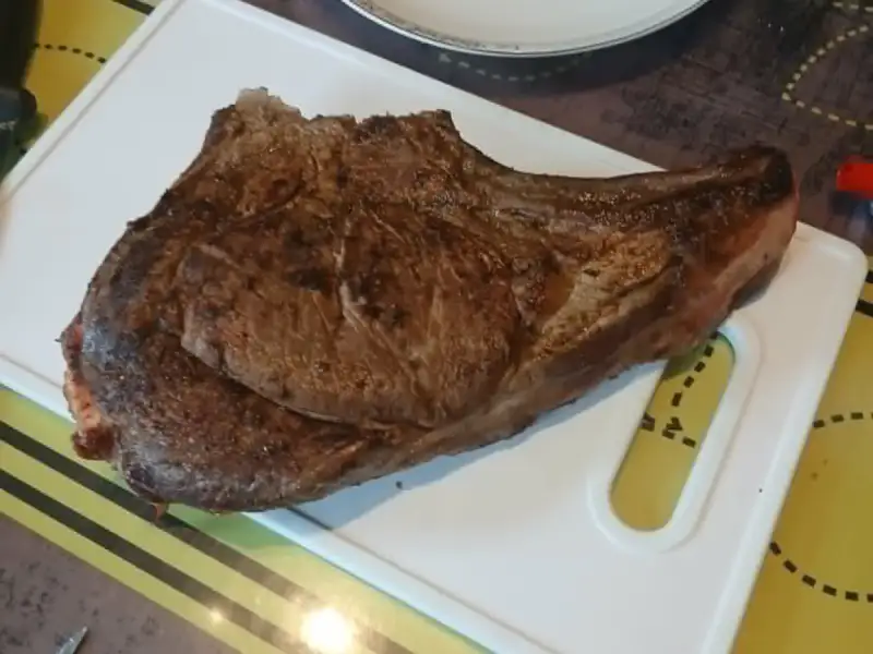 Chuletón de res asado sobre una tabla para cortar blanca
