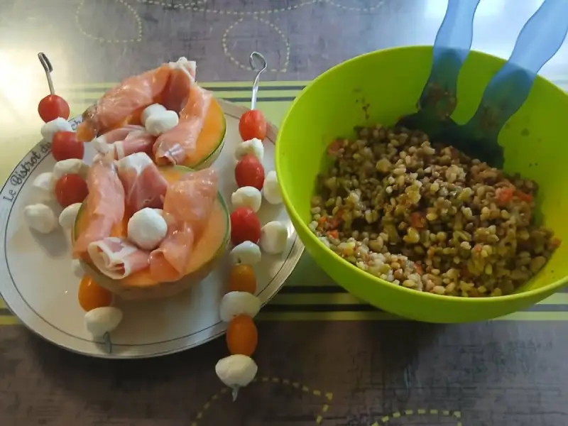 Medios melones rellenos de jamón serrano y bolitas de mozzarella, brochetas de tomates cherry y mozzarella, junto a una ensaladera
