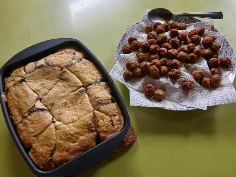 Panqué de cerezas dorado en un molde cuadrado, junto a un plato de albondiguitas